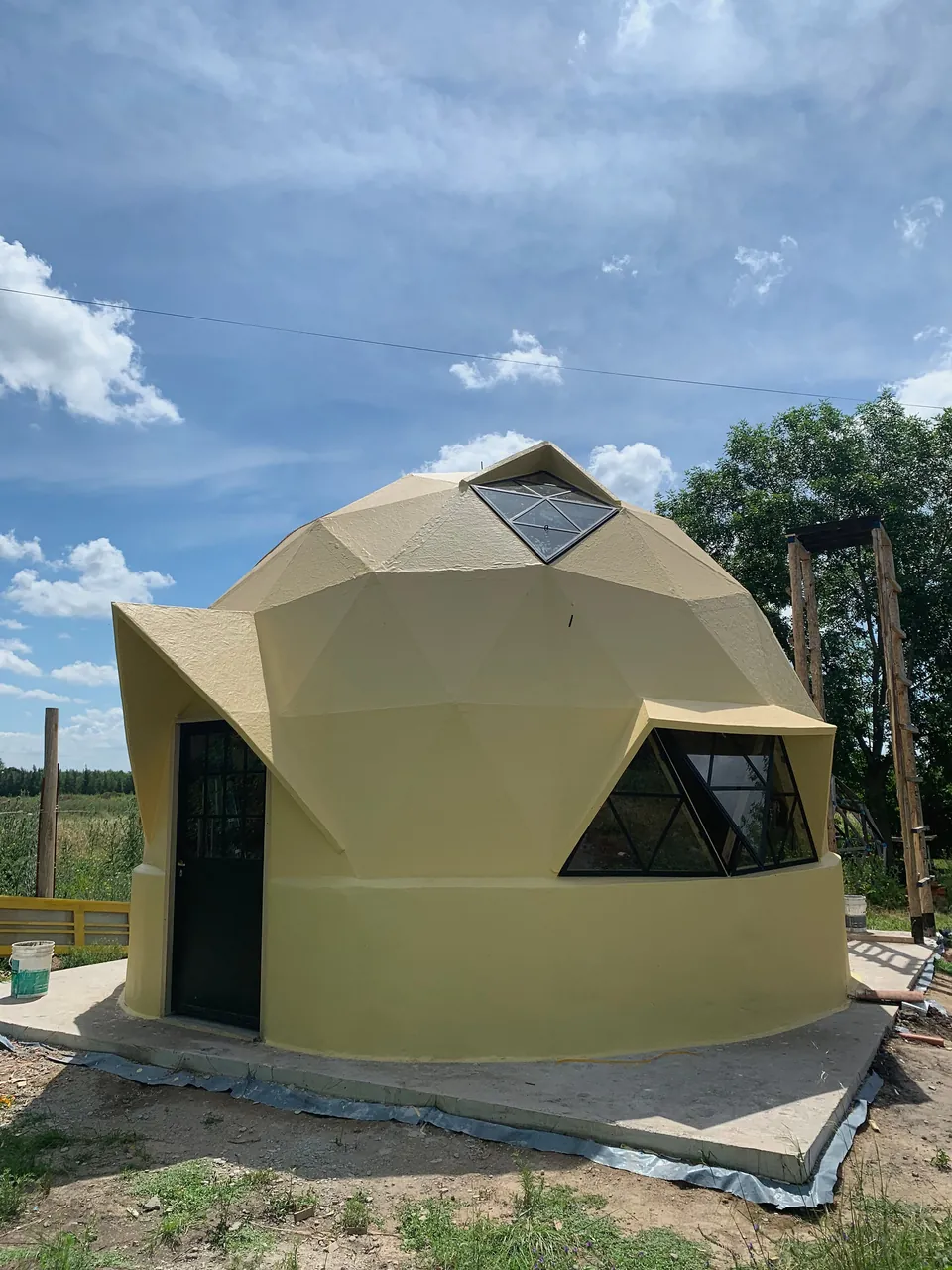 LunTao, domo amarillo con puerta oscura y ventana triangular bajo cielo nuboso